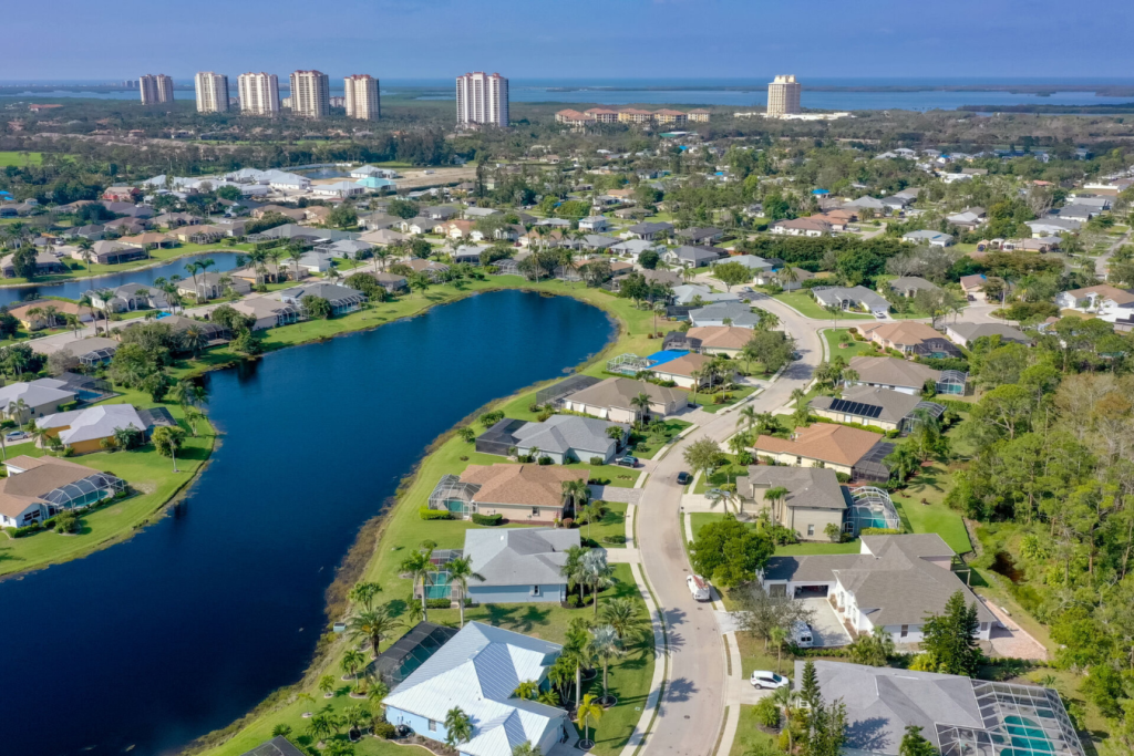 Aerial view of an Estero, Florida lakeside neighbourhood with high-rise towers and the bay beyond