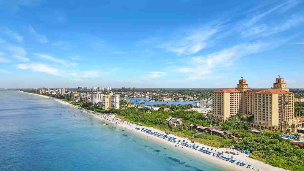 Aerial view of the Naples, Florida shoreline with rows of beach umbrellas and beachfront resorts
