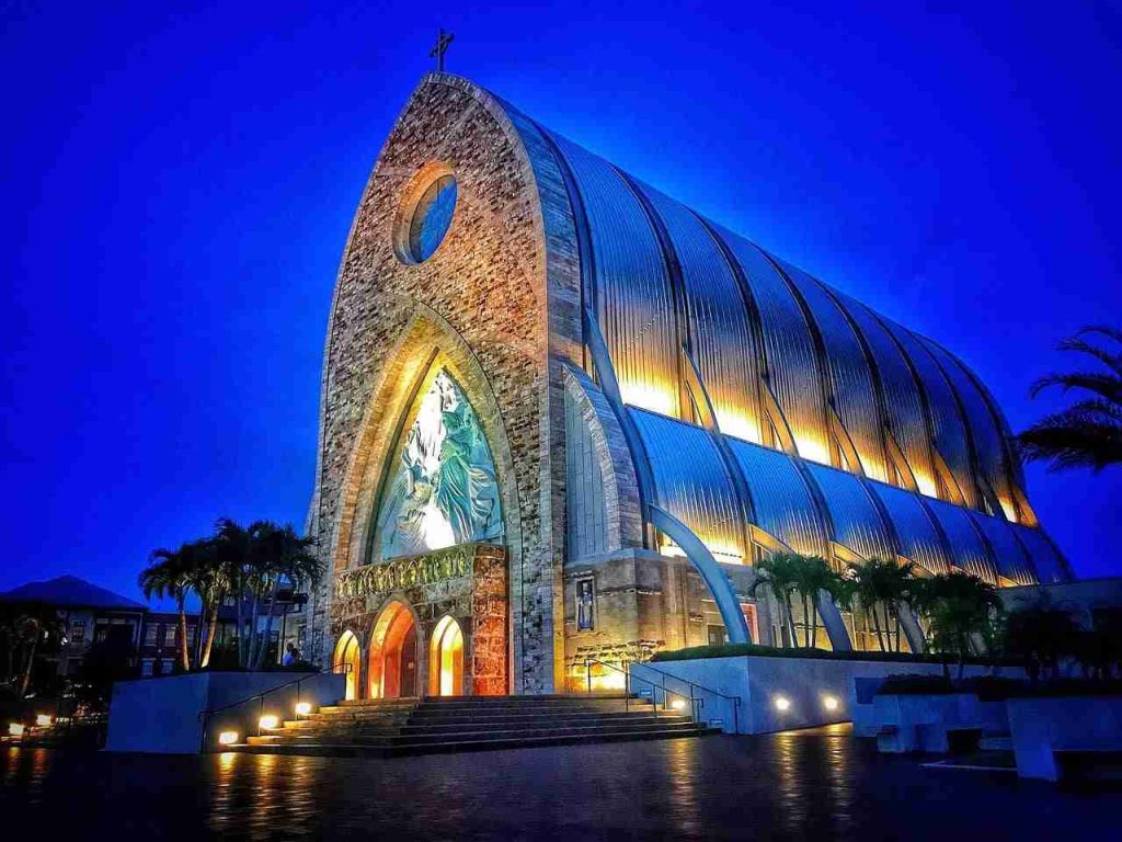 The Ave Maria Oratory lit against a deep blue sky at dusk in Ave Maria, Florida