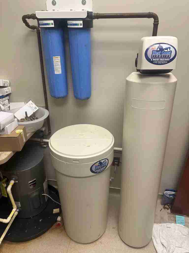 A whole-house water softener system installed beside a home